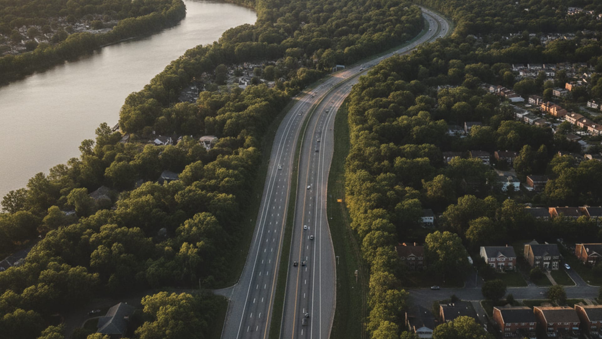 Aerial view of the DC area freeway network at golden hour showing the I-495 Capital Beltway, the Potomac, and wooded inner suburbs